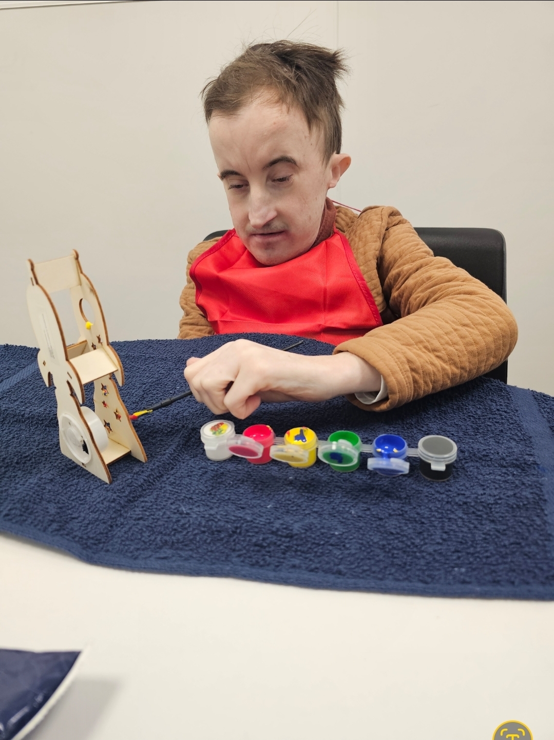 Ben smiling while creating colorful artwork during an Illuminate Care activity